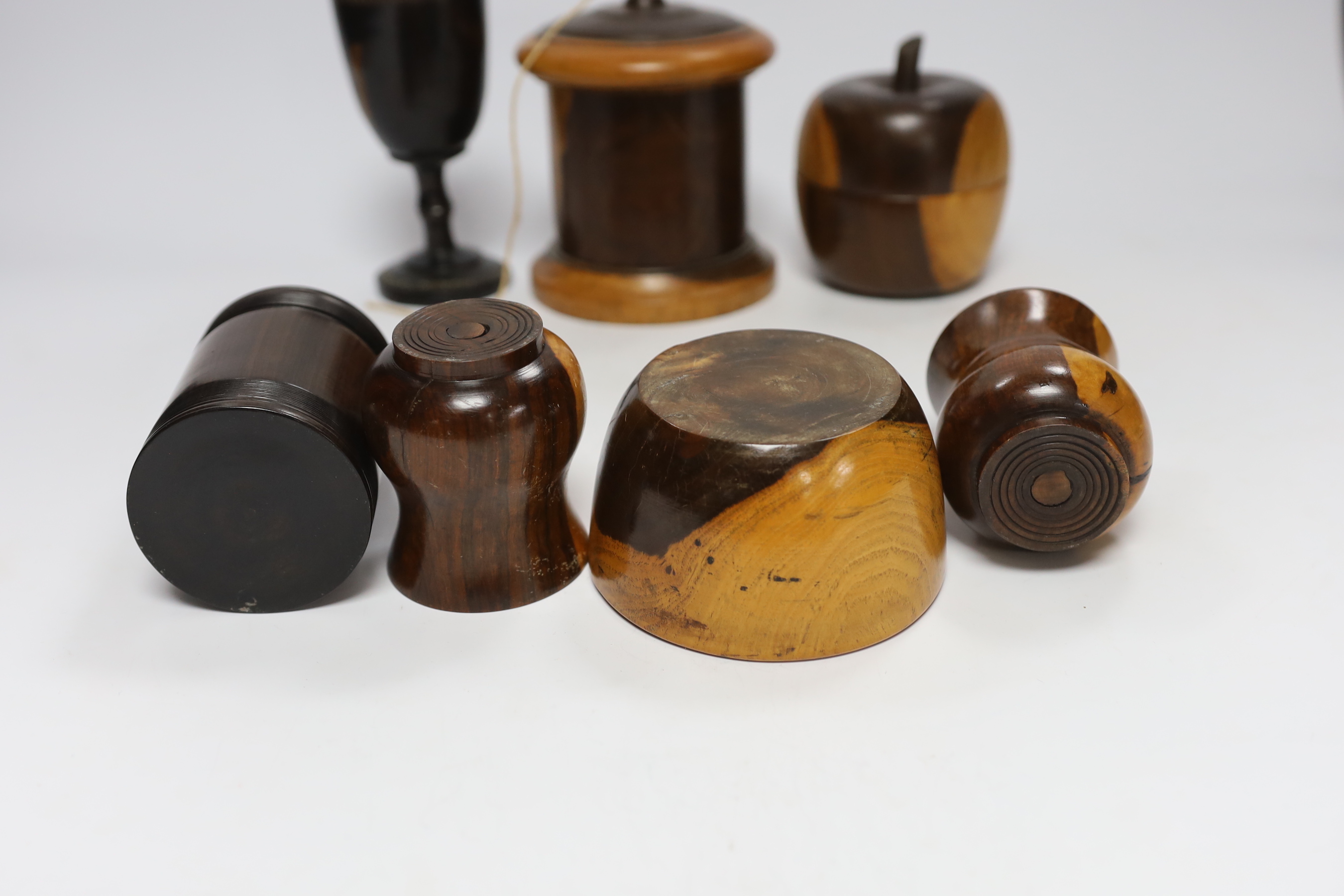 A collection of 19th/20th century lignum vitae vessels, including a turned string box and cover, an apple shaped box and cover, two vases, a mortar, a goblet and a box and cover (7)